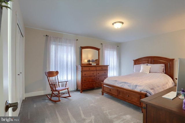 bedroom with baseboards, a closet, and light carpet