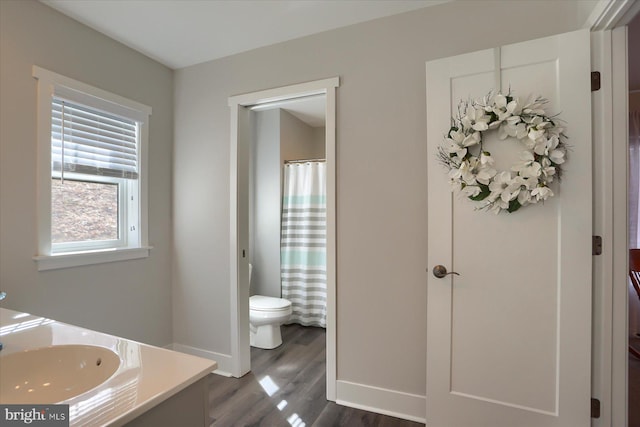 bathroom featuring toilet, vanity, baseboards, and wood finished floors