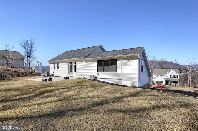 view of front of home with central air condition unit, entry steps, a front yard, roof with shingles, and a patio area