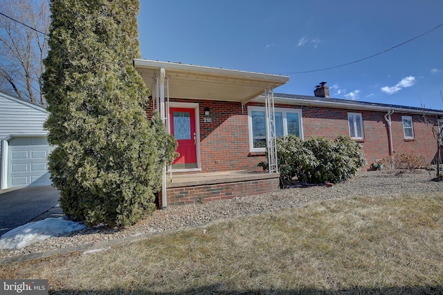 view of front facade featuring a garage, covered porch, brick siding, and a chimney