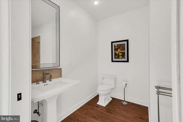 bathroom featuring visible vents, baseboards, toilet, decorative backsplash, and wood finished floors