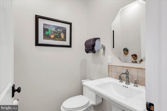 bathroom featuring a sink, tasteful backsplash, and toilet