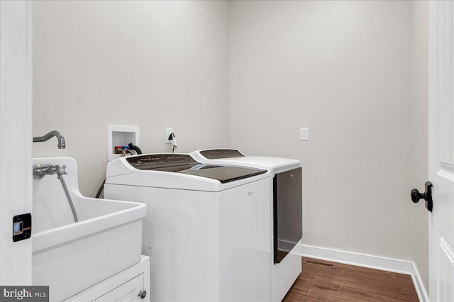 laundry area featuring baseboards, dark wood finished floors, laundry area, independent washer and dryer, and a sink