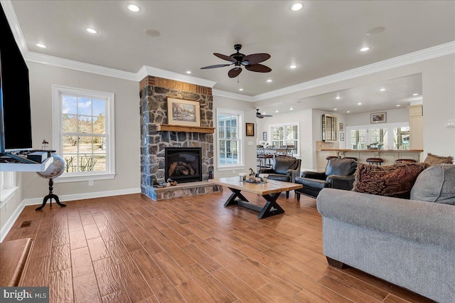 living room featuring baseboards, light wood-style flooring, a fireplace, and ornamental molding