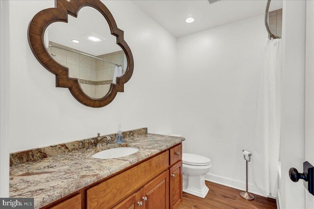 bathroom featuring vanity, a shower with shower curtain, wood finished floors, baseboards, and toilet