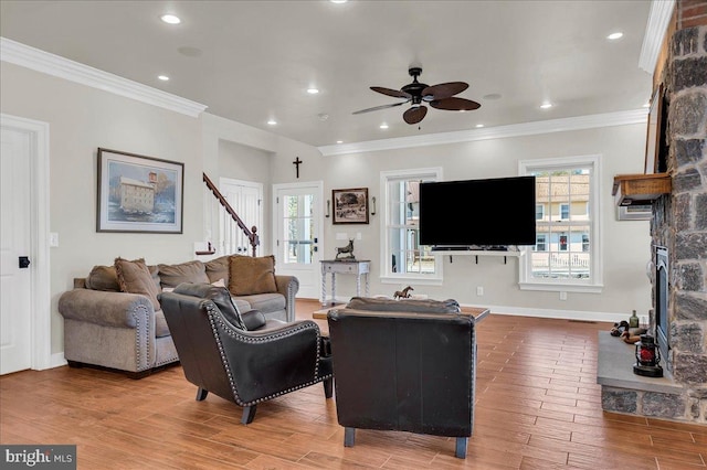 living room featuring plenty of natural light, wood finished floors, a fireplace, and crown molding