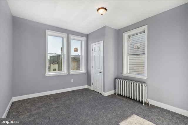 unfurnished room with radiator, baseboards, and dark colored carpet