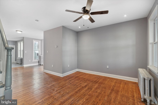 empty room featuring radiator heating unit, baseboards, and wood finished floors