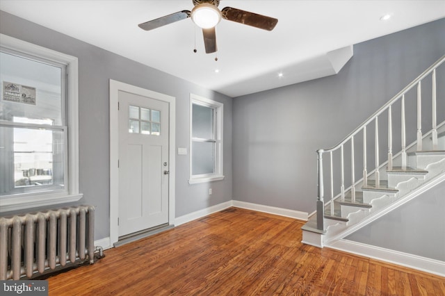 entrance foyer featuring ceiling fan, baseboards, stairs, radiator heating unit, and wood finished floors