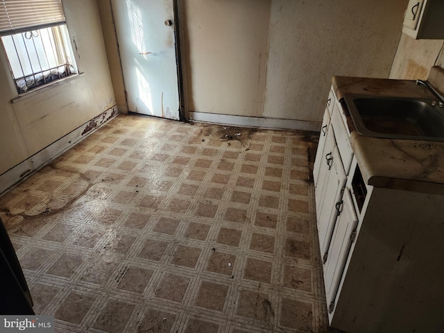 kitchen with light floors, white cabinetry, and a sink