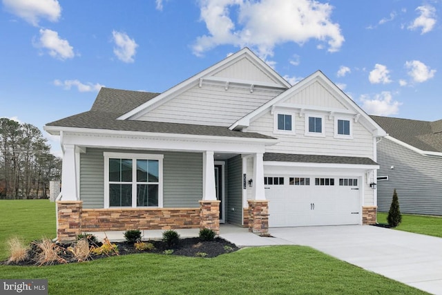 craftsman-style home with a front yard, driveway, roof with shingles, an attached garage, and stone siding