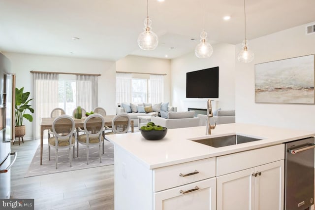 kitchen with a sink, pendant lighting, a wealth of natural light, and light wood finished floors