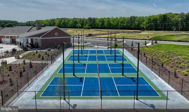 view of sport court with fence and a wooded view