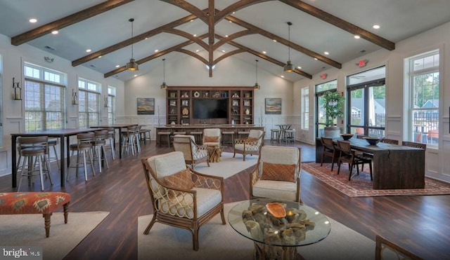 living room with beamed ceiling, plenty of natural light, high vaulted ceiling, and wainscoting