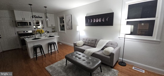 living room with baseboards, visible vents, and dark wood-style flooring