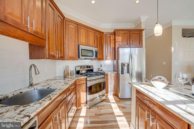 kitchen with brown cabinets, pendant lighting, ornamental molding, a sink, and stainless steel appliances