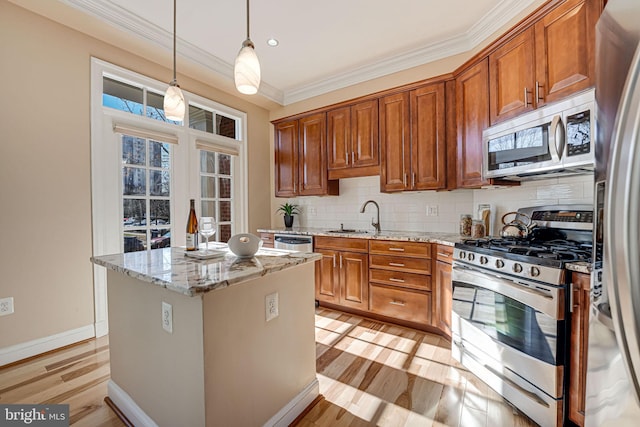 kitchen with ornamental molding, a sink, appliances with stainless steel finishes, light wood finished floors, and decorative backsplash