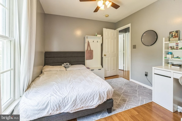 bedroom with a ceiling fan, baseboards, and wood finished floors