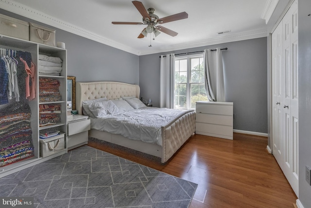 bedroom with a closet, visible vents, crown molding, and dark wood-type flooring