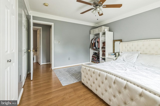 bedroom featuring light wood-style flooring, ornamental molding, a closet, baseboards, and ceiling fan