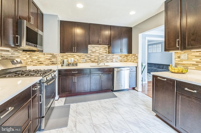 kitchen with marble finish floor, stainless steel appliances, light countertops, and a sink