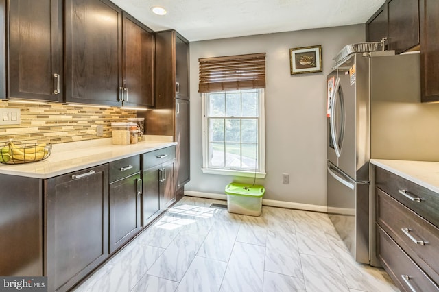 kitchen featuring dark brown cabinetry, light countertops, tasteful backsplash, and freestanding refrigerator