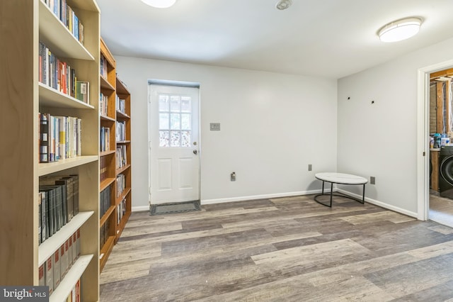 foyer entrance featuring washer / clothes dryer, wood finished floors, and baseboards