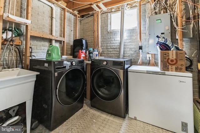 laundry room with laundry area, electric panel, separate washer and dryer, and brick wall