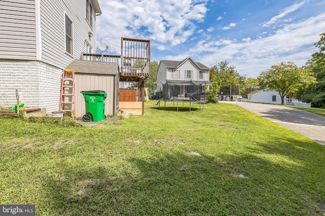 view of yard featuring a wooden deck, an outbuilding, a trampoline, and a storage shed