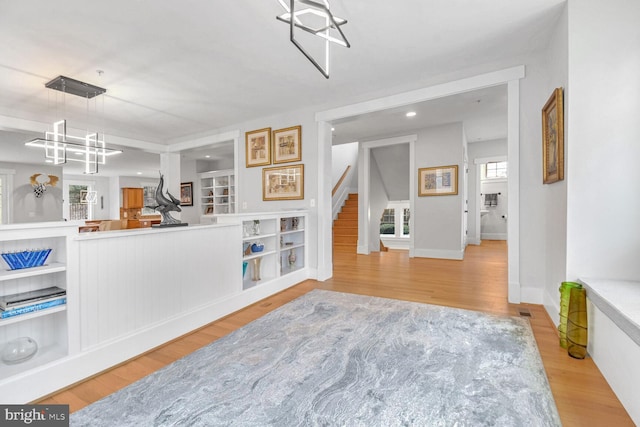 living room with wood finished floors, recessed lighting, an inviting chandelier, baseboards, and stairs