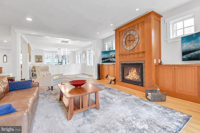 living area with a glass covered fireplace, recessed lighting, and wood finished floors