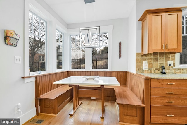 dining area with a wainscoted wall, light wood-style floors, visible vents, and breakfast area