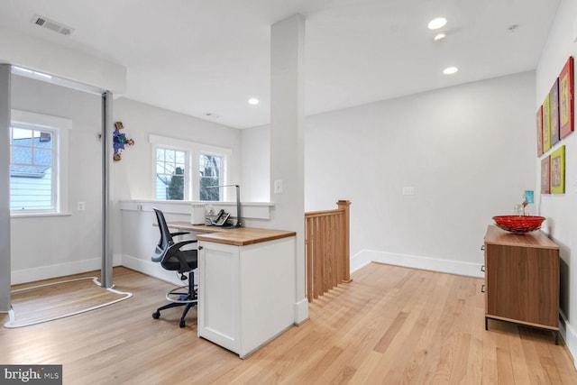 home office with visible vents, plenty of natural light, and light wood-type flooring