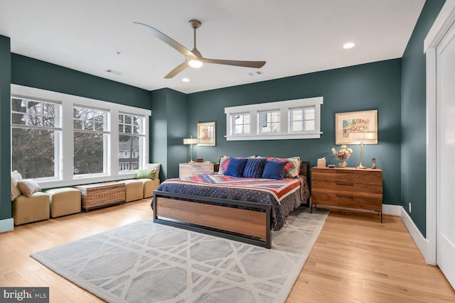 bedroom with baseboards, multiple windows, and wood finished floors