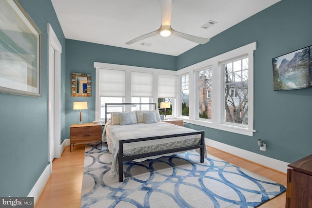 bedroom with light wood finished floors, visible vents, and baseboards