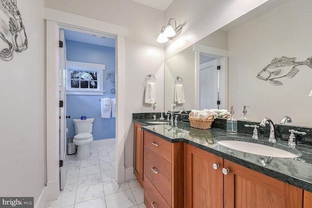 full bathroom with double vanity, toilet, marble finish floor, and a sink