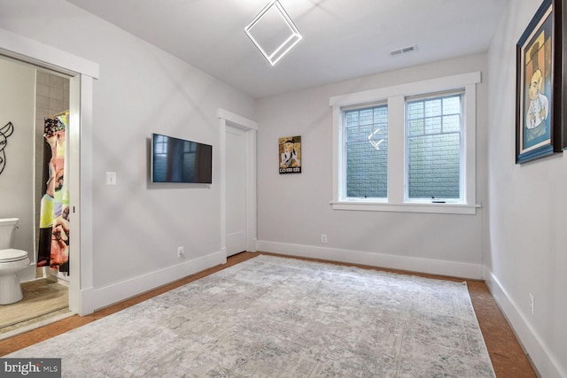 unfurnished bedroom featuring a closet, ensuite bathroom, and baseboards