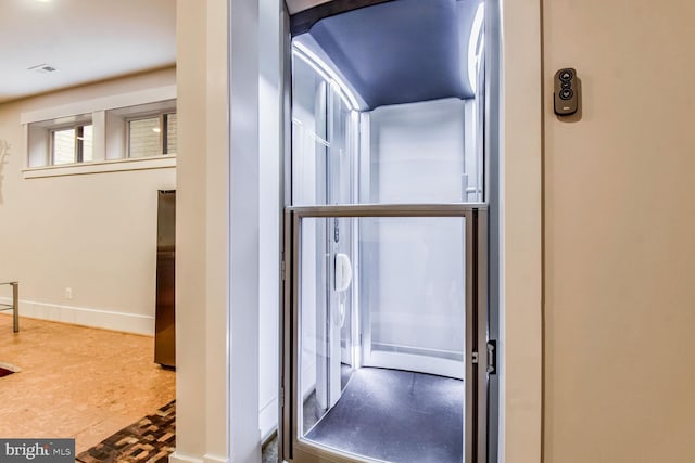 hall with baseboards, elevator, and visible vents