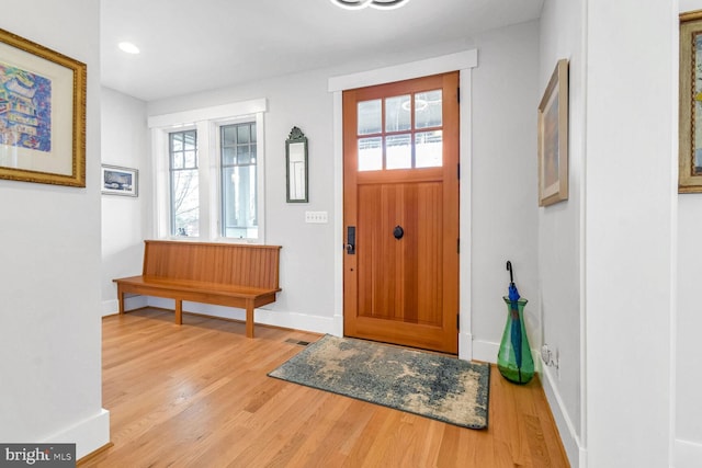 foyer entrance with baseboards, a healthy amount of sunlight, and wood finished floors