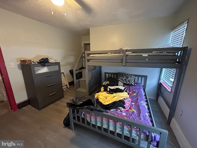 bedroom with ceiling fan, baseboards, a textured ceiling, and wood finished floors