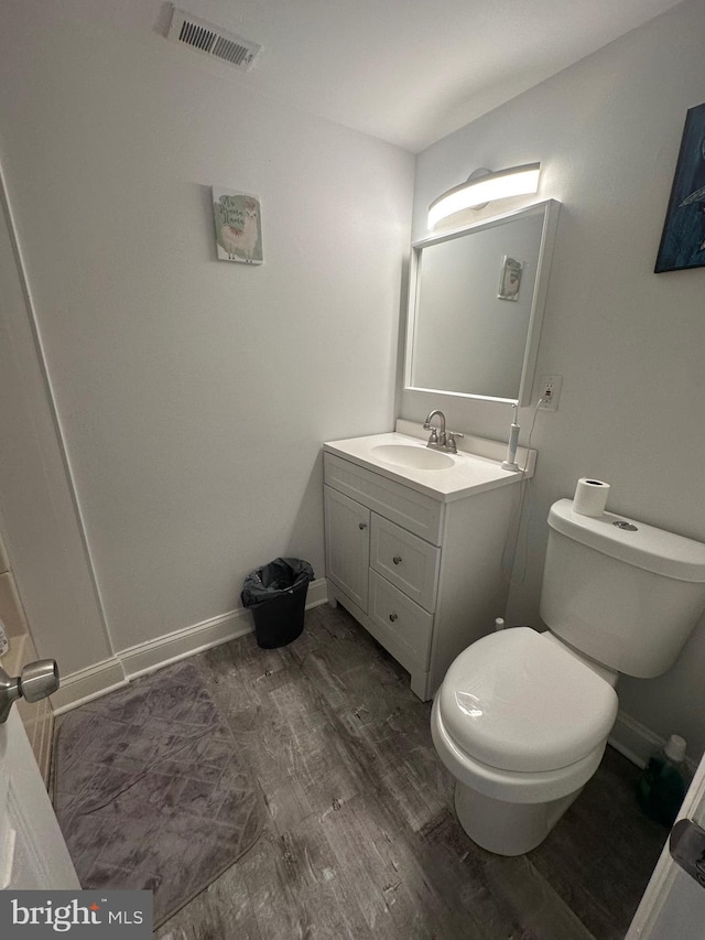 bathroom featuring visible vents, toilet, wood finished floors, baseboards, and vanity