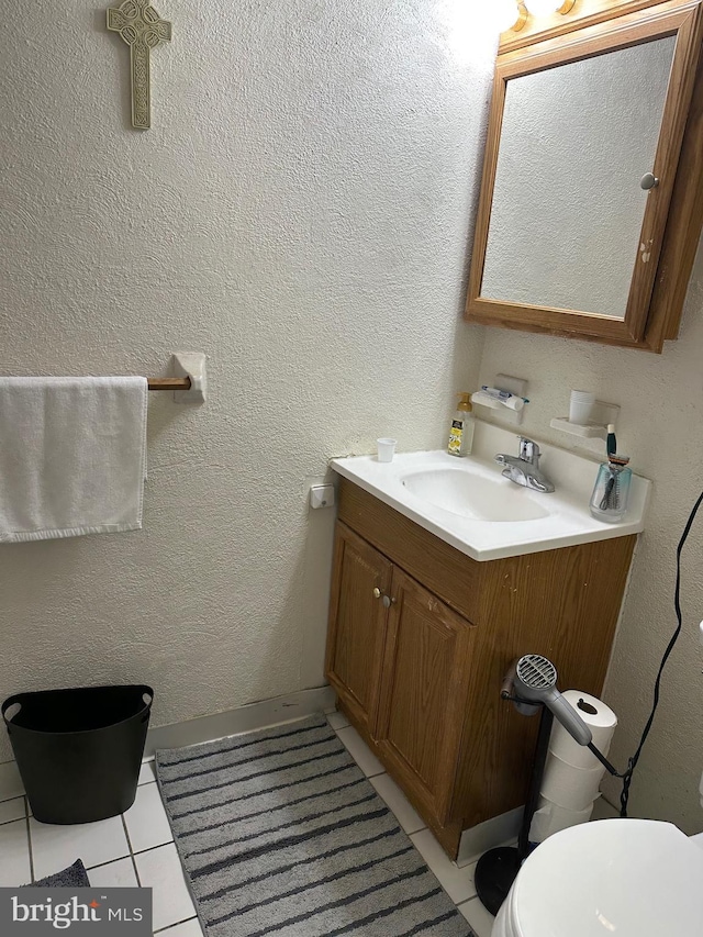 half bath featuring a textured wall, toilet, vanity, and tile patterned flooring