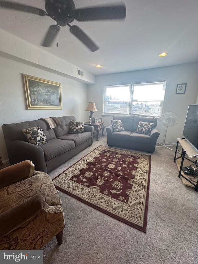 living area featuring visible vents, a ceiling fan, and carpet