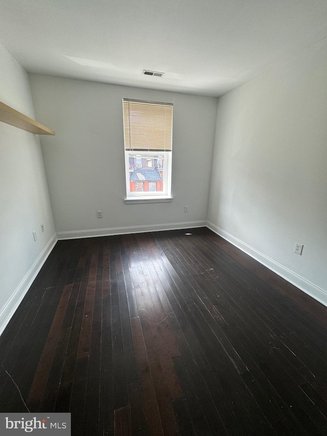 spare room featuring hardwood / wood-style flooring, baseboards, and visible vents