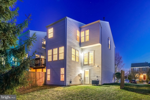 back of house at twilight featuring central AC and a yard