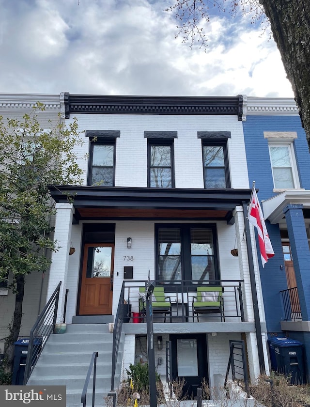 multi unit property with brick siding and a porch