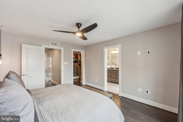 bedroom with visible vents, a walk in closet, baseboards, a closet, and dark wood-style flooring