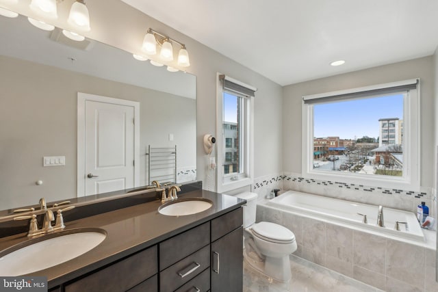 full bathroom with a sink, a garden tub, double vanity, and toilet