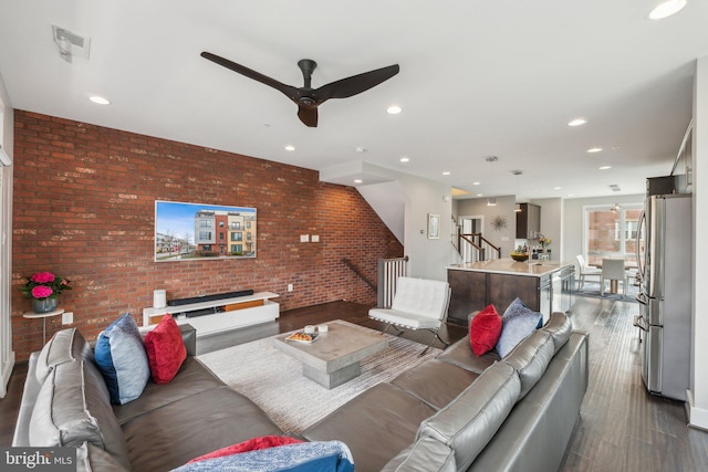 living area featuring visible vents, brick wall, stairway, recessed lighting, and wood finished floors