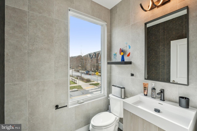 half bathroom featuring a sink, backsplash, toilet, and tile walls